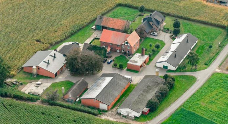 Luftaufnahme eines landwirtschaftlichen Areals mit mehreren Gebäuden und Weideland in Rietberg.