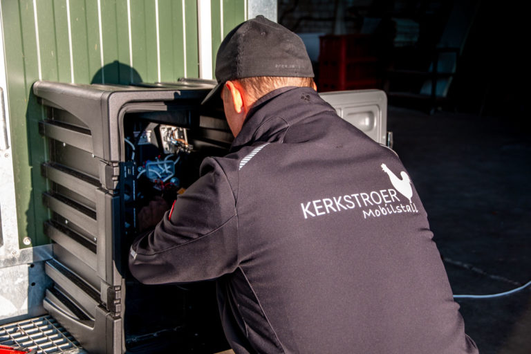 Ein Mitarbeiter von Kerkstroer Mobilstall arbeitet an der Elektronik eines mobilen Hühnerstalls.