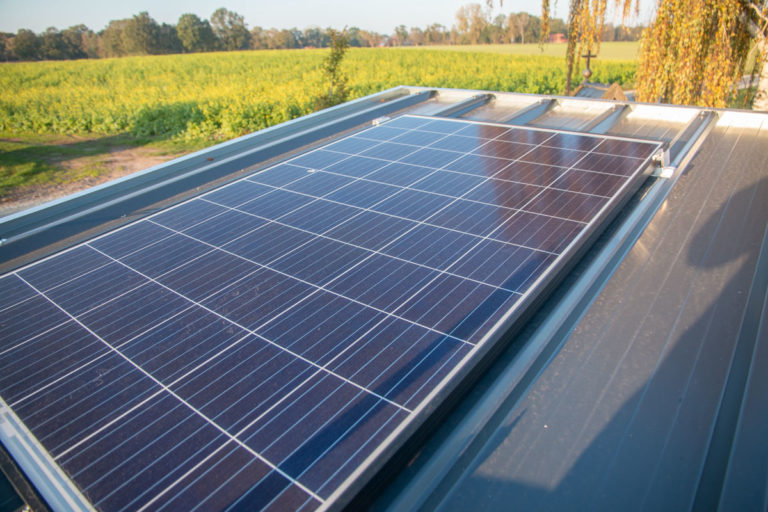 Ein Solar-panel auf dem Dach eines mobilen Hühnerstalles mit einer ländlichen Kulisse im Hintergrund.